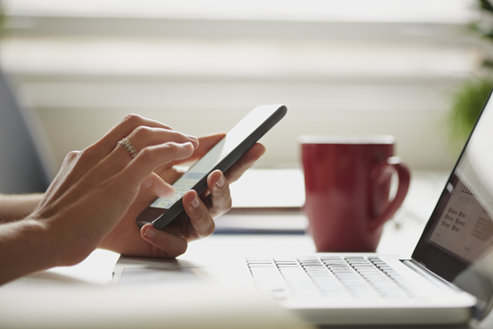 a person using a phone and laptop